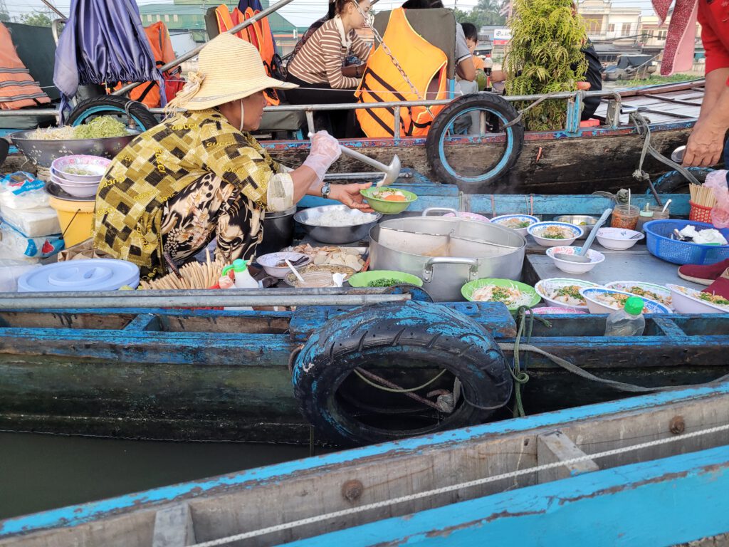 Vietnamesin serviert Nudelsuppe in einem Boot
